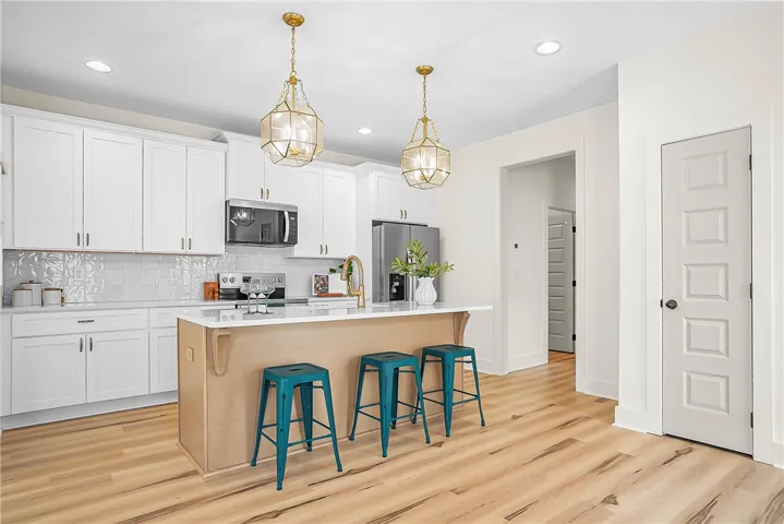 A well-lit kitchen with sleek white cabinetry and a central island creates an inviting space for hosting.