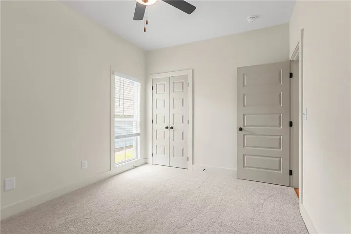A comfortable guest bedroom features carpeted flooring and a convenient ceiling fan for optimal comfort.