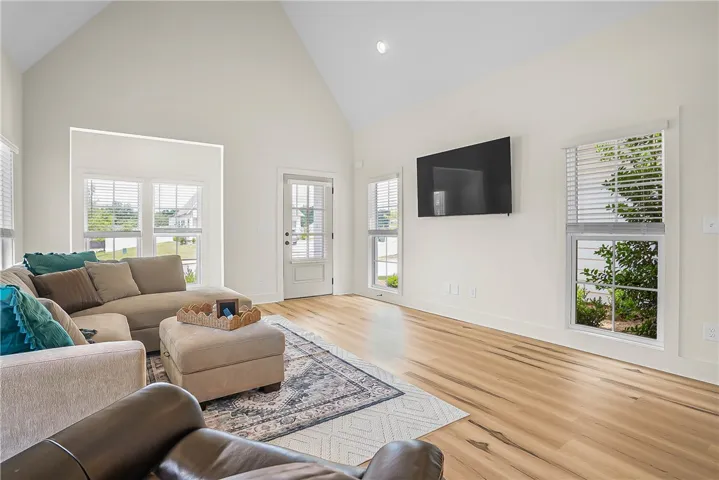 A spacious living area features high vaulted ceilings and luxury vinyl plank flooring.