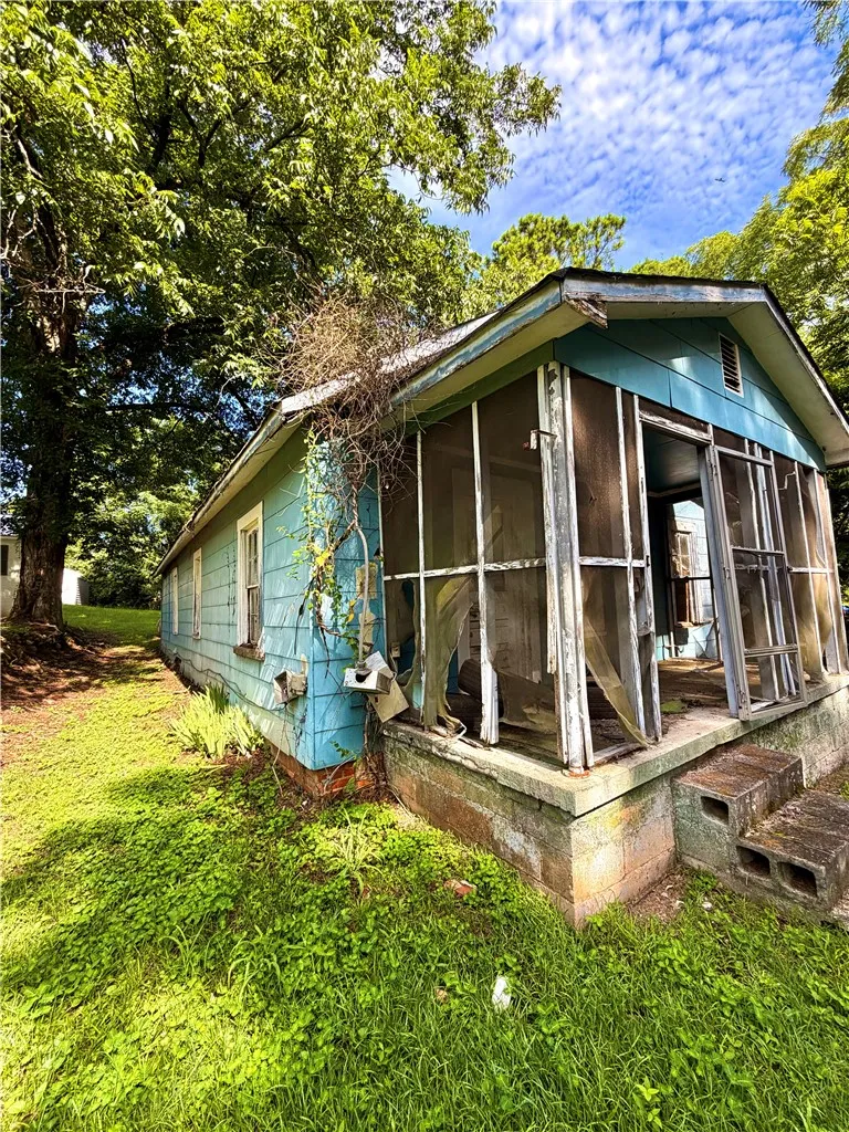 A charming home awaits renovation, featuring a screened porch and mature trees.