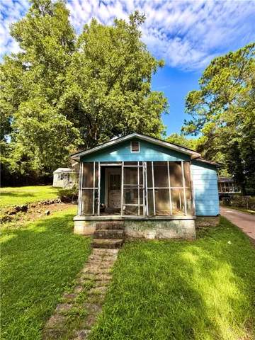 A charming home awaits with a serene screened porch and verdant surroundings.