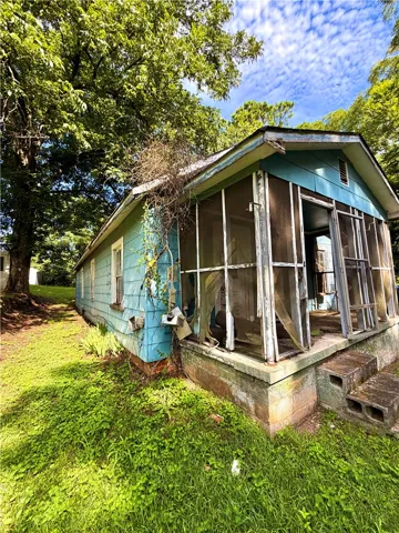A charming home awaits renovation, featuring a screened porch and mature trees.