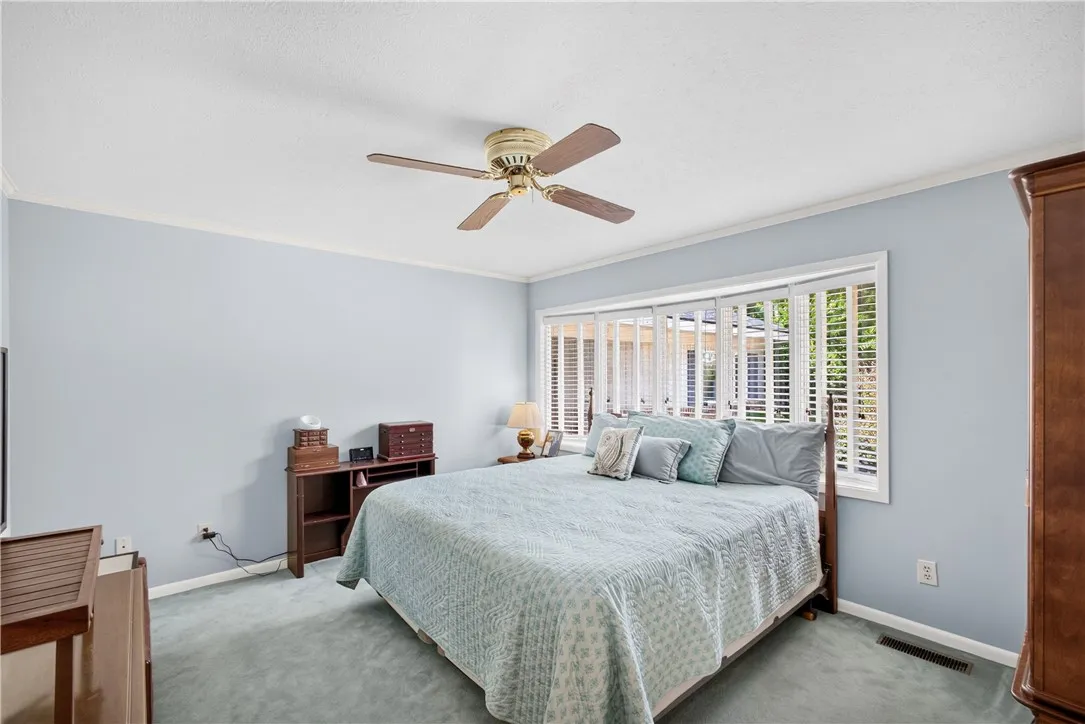 A comforting bedroom space features soft blue walls and a refreshing ceiling fan above.