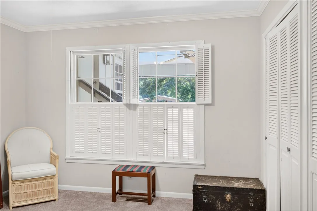 Well-lit room featuring multiple windows adorned with classic plantation shutters and carpeted flooring.