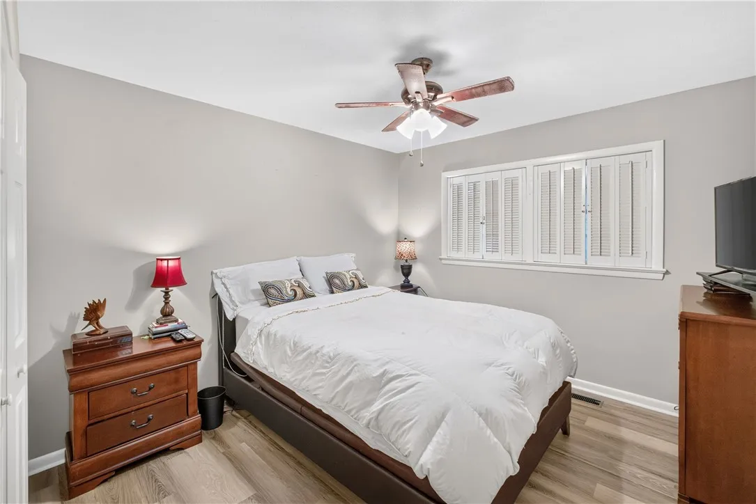 A comforting bedroom with warm flooring and a ceiling fan for optimal airflow.