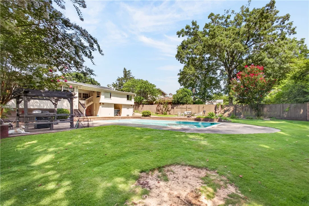 An inviting backyard oasis offers a sparkling in-ground pool and ample green space for leisure and entertainment.