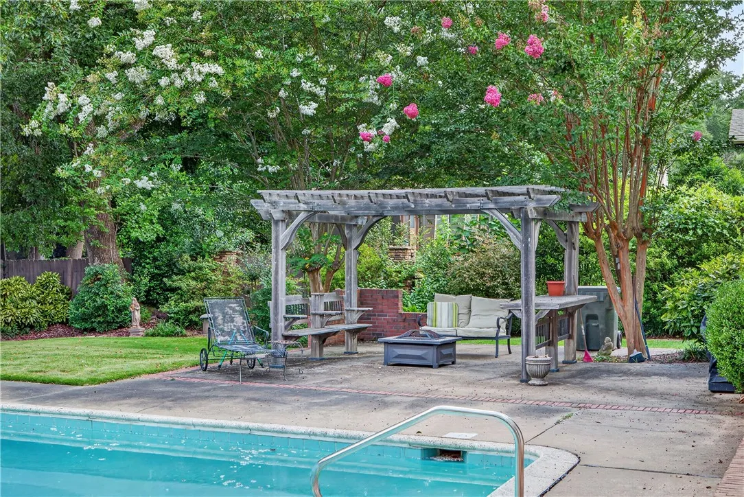 An inviting backyard oasis offers a sparkling pool and a shaded pergola for leisurely outdoor gatherings.