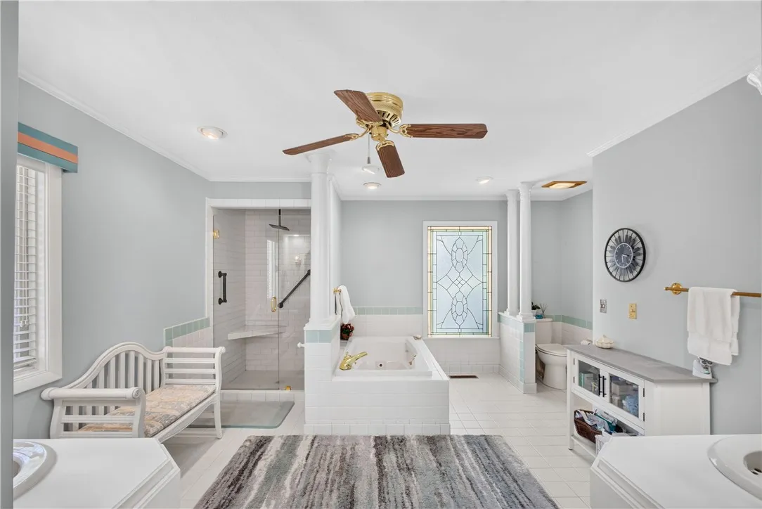 Luxurious bathing retreat boasts a glass-enclosed shower, deep soaking tub, and elegant tile work.