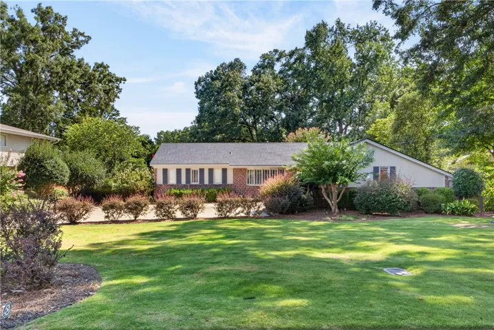 A traditional brick and siding home features manicured landscaping and a verdant lawn.