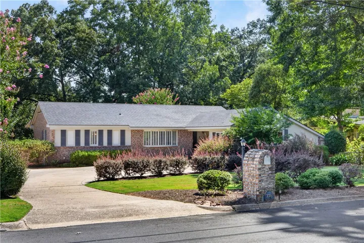 Mature trees and lush landscaping frame this traditional brick home with a welcoming driveway.