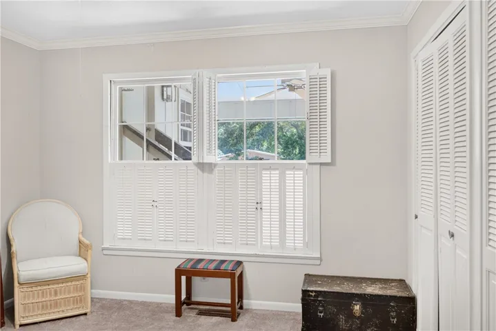 Well-lit room featuring multiple windows adorned with classic plantation shutters and carpeted flooring.