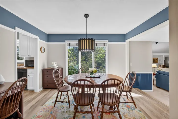 A well-lit dining area offers ample space for gathering, featuring elegant flooring and an open flow.