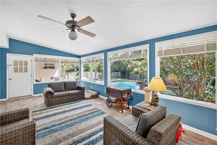 Sun-filled room with large windows offers serene backyard views and refreshing pool access.