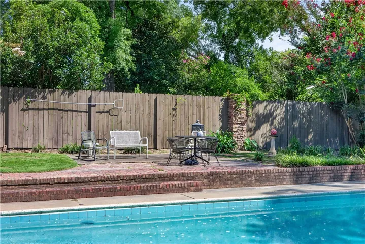 A tranquil backyard oasis features a glistening pool, brick patio, and a private fenced yard.