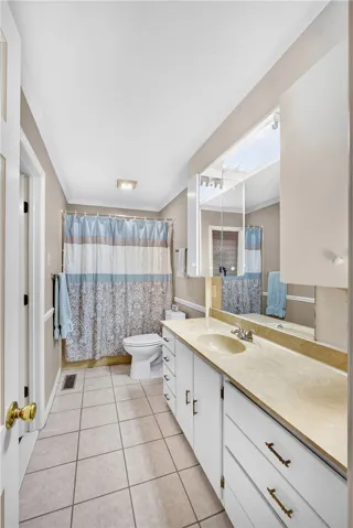 A compact full bathroom featuring a long vanity with a single sink and a combination tub-shower.