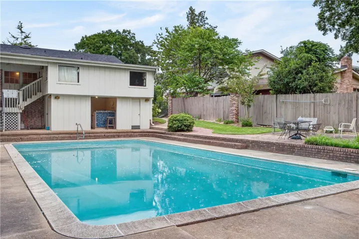 A private backyard oasis features a glistening inground pool, inviting outdoor living, and a convenient poolside bar.