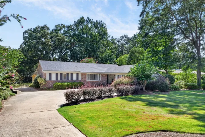 A classic brick-front residence featuring a manicured lawn and mature trees, offering timeless curb appeal.