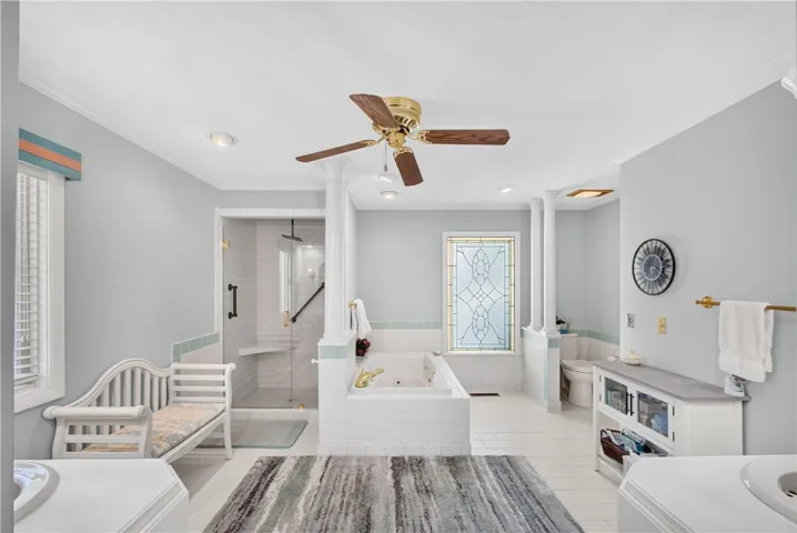 Luxurious bathing retreat boasts a glass-enclosed shower, deep soaking tub, and elegant tile work.