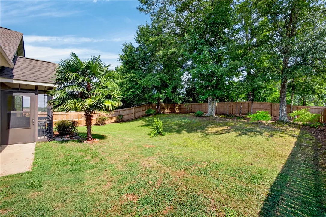 A fully fenced backyard retreat offers a private, shaded lawn and mature landscaping.