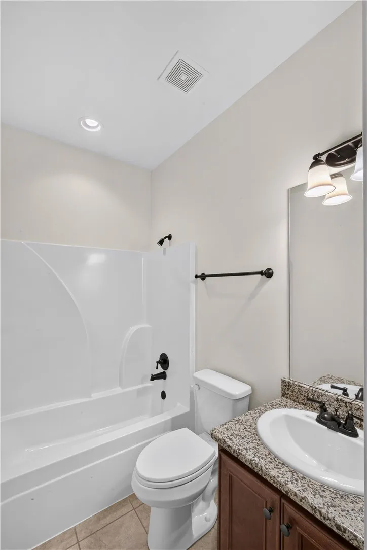 Functional full bathroom featuring a tub-shower combination, a vanity with a sink, and tile flooring.