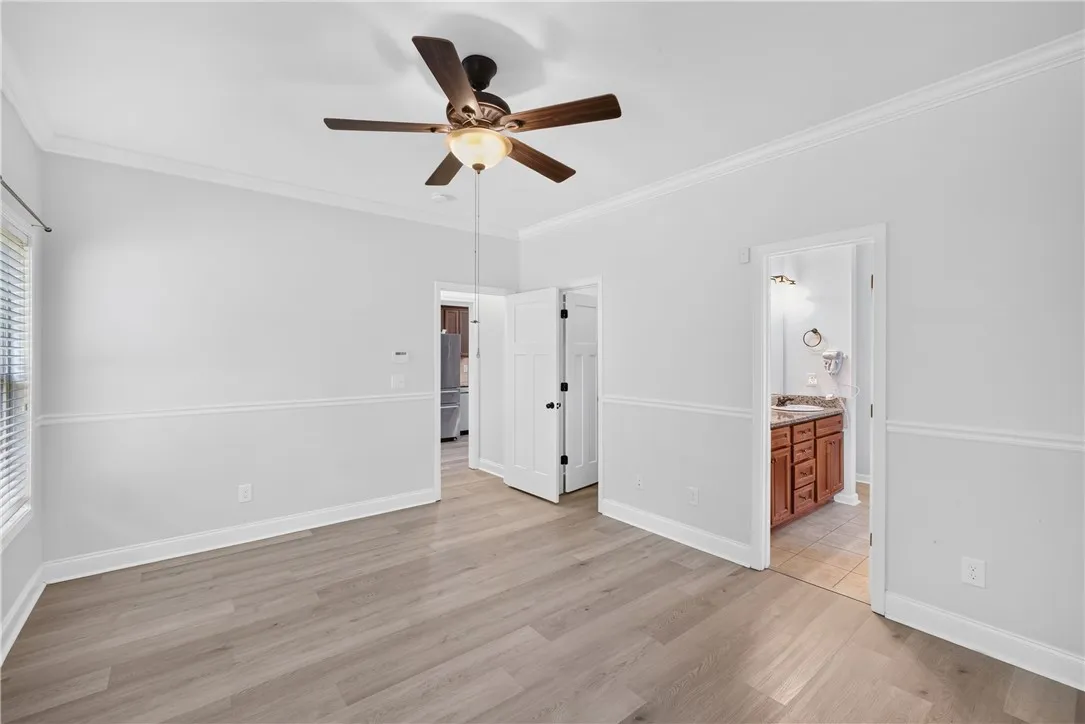 A well-lit room features light wood flooring and a classic ceiling fan, offering a harmonious blend of comfort and style.