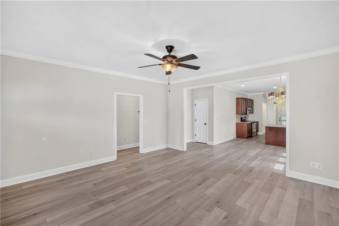 A well-lit interior space features resilient flooring, a kitchen view, and a ceiling fan.