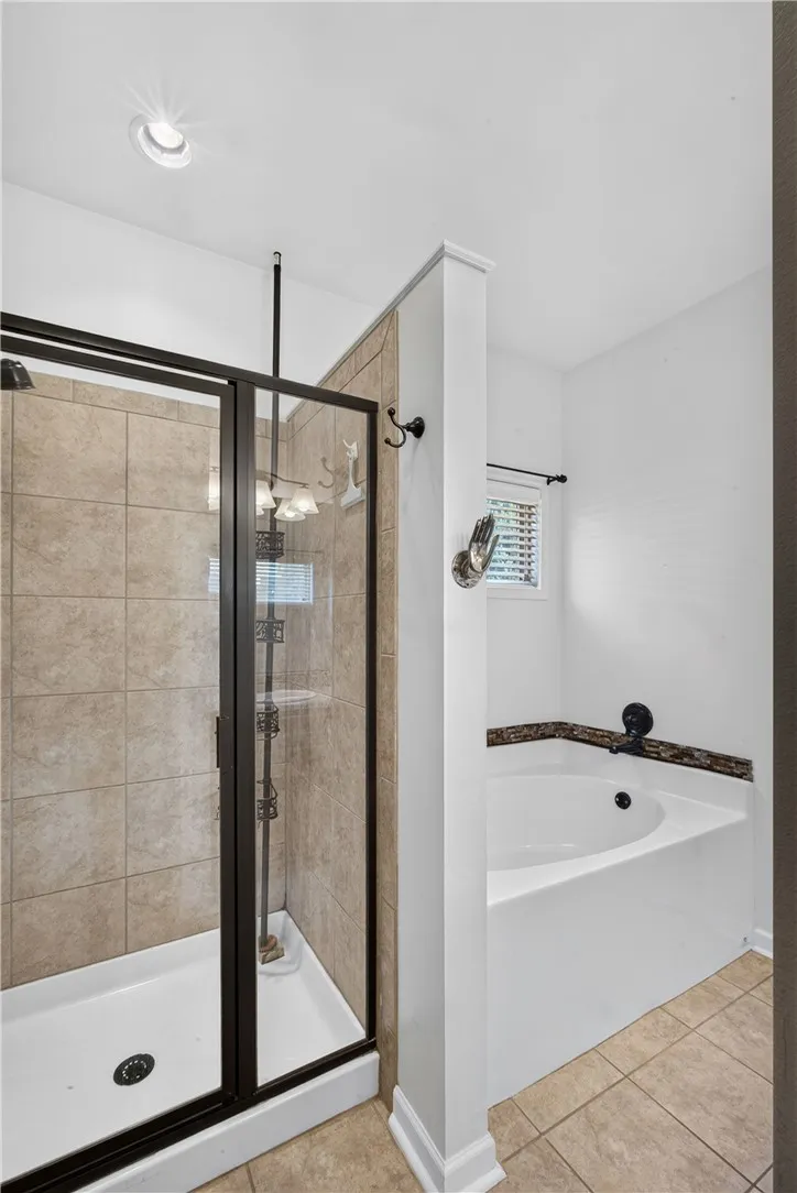 A well-appointed bathroom offers a glass-enclosed shower and a separate soaking tub.