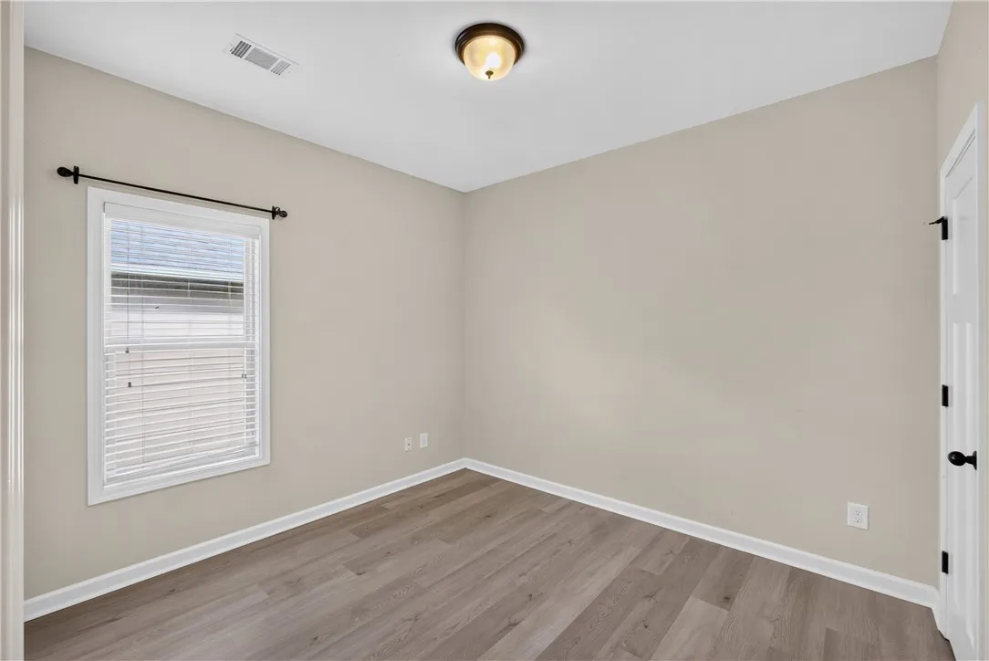 A well-lit room with wood-look flooring and a window offering natural light.