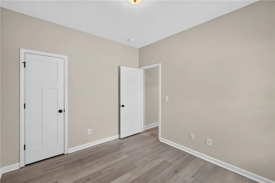 A quiet bedroom with contemporary wood-look flooring and ample wall space awaits personalization.
