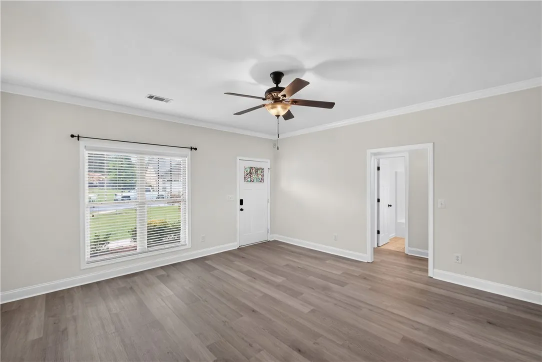 A welcoming entry space with fresh flooring, a decorative glass front door, and an overhead ceiling fan.