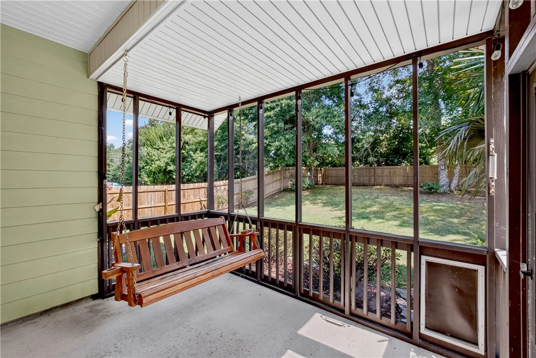 A screened porch offers a tranquil retreat with a backyard view and ample room for relaxation.