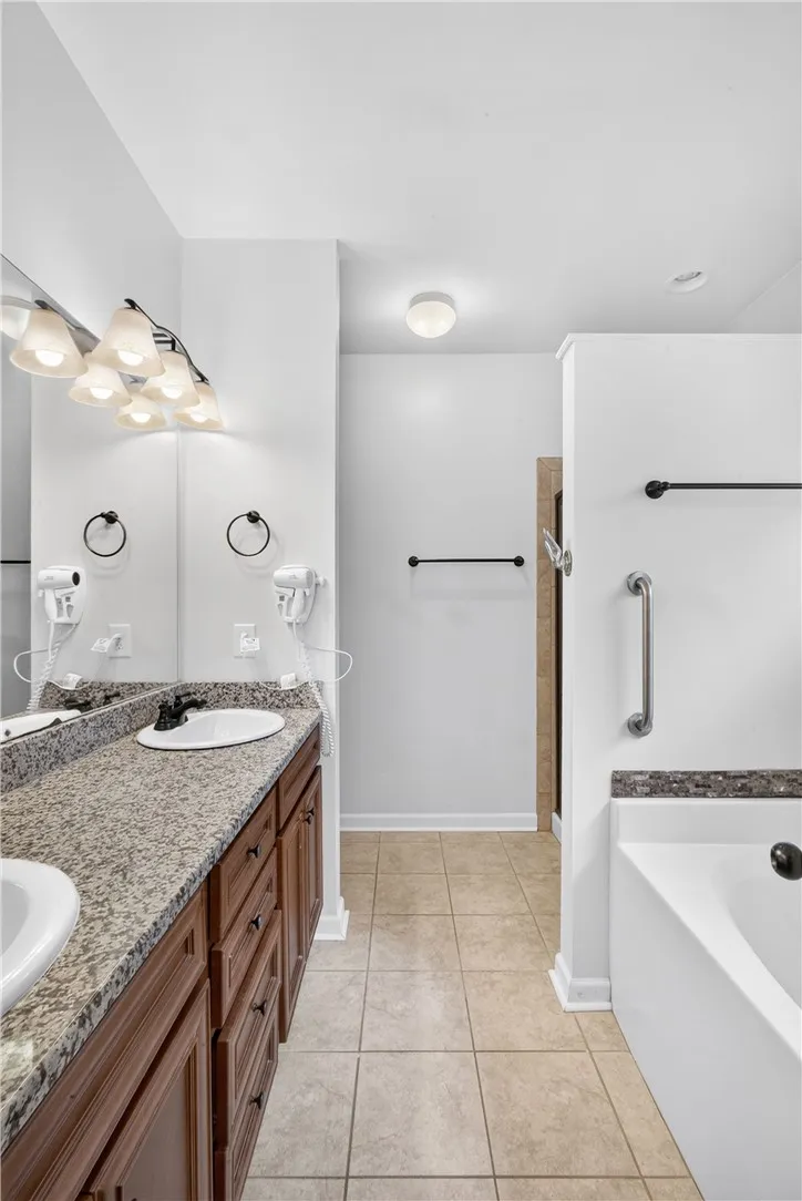 Granite counters and dual sinks define this bright, well-appointed primary bathroom.