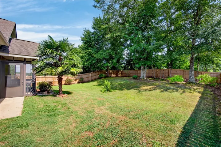 A fully fenced backyard retreat offers a private, shaded lawn and mature landscaping.
