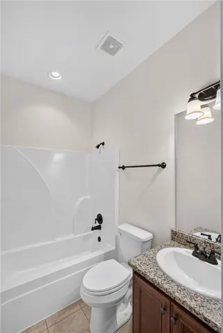 Functional full bathroom featuring a tub-shower combination, a vanity with a sink, and tile flooring.