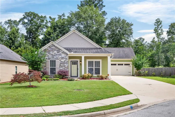 Green siding and stone accents welcome you home to this charming residence with a well-manicured front yard.