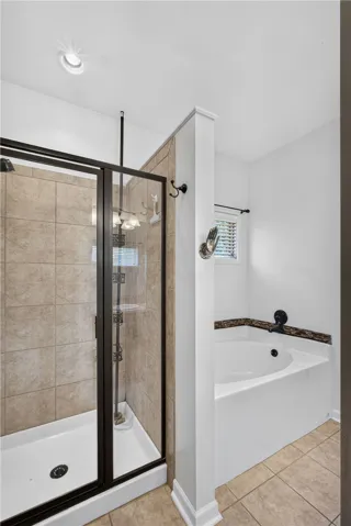 A well-appointed bathroom offers a glass-enclosed shower and a separate soaking tub.
