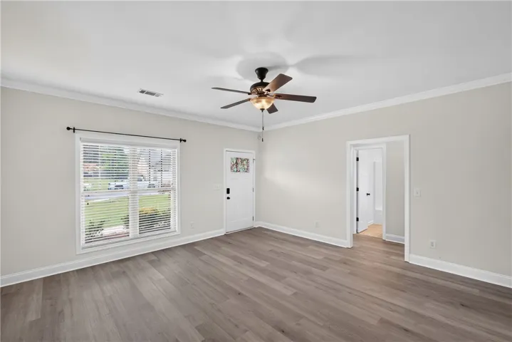 A welcoming entry space with fresh flooring, a decorative glass front door, and an overhead ceiling fan.