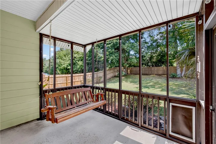 A screened porch offers a tranquil retreat with a backyard view and ample room for relaxation.