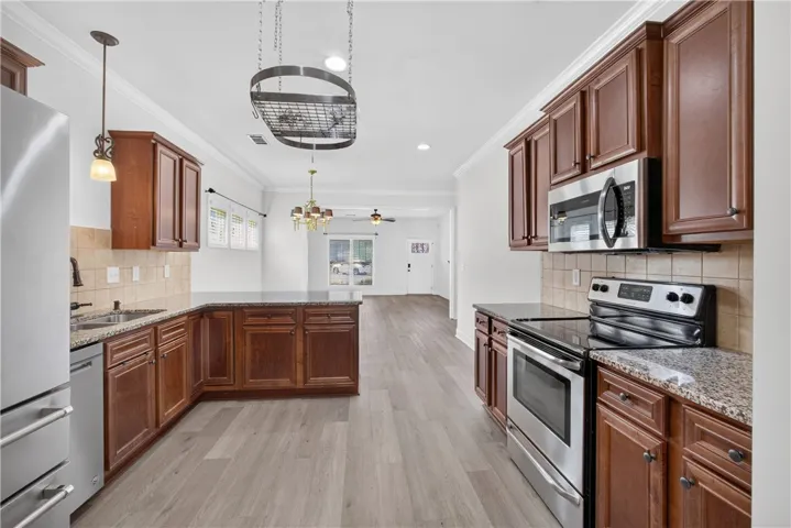 A well-appointed kitchen features stainless steel appliances, granite countertops, and rich wood cabinetry, with an open layout overlooking a spacious living area.