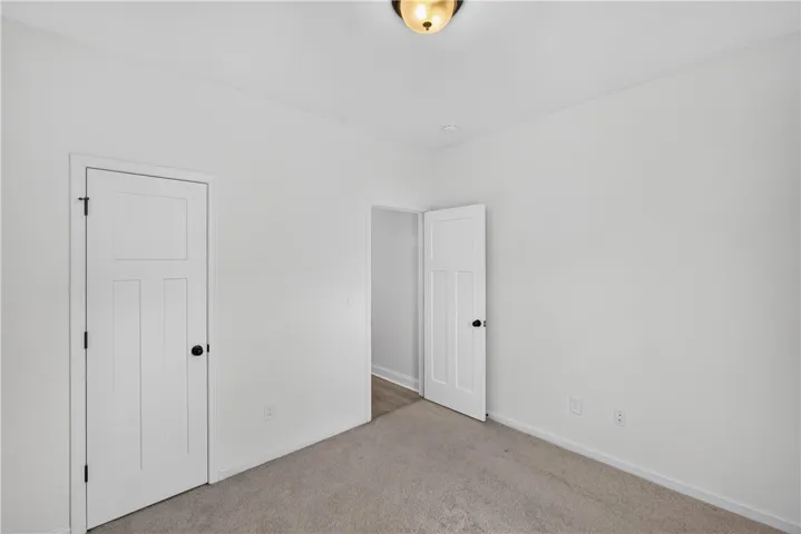 A well-proportioned bedroom features soft carpeting and classic paneled doors, creating a serene personal retreat.