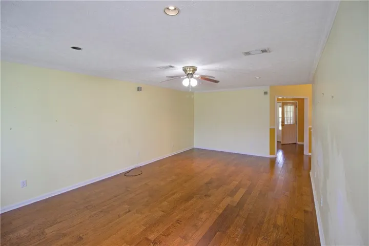 Bright hardwood flooring flows through this ample living space, featuring recessed lighting and a ceiling fan.