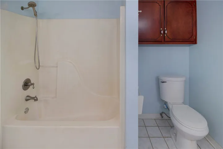 Functional full bathroom featuring a tub-shower combination and overhead cabinetry.