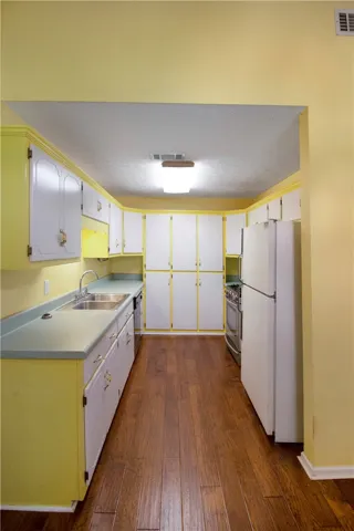 Well-lit kitchen with rich wood flooring and ample cabinetry provides functional cooking space.