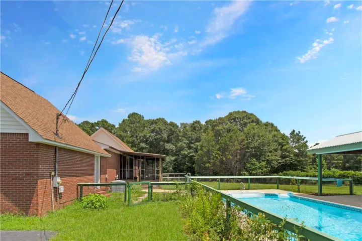 A private swimming pool and covered porch await, nestled beside the home with mature trees providing a serene backdrop.