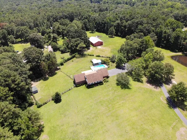 An aerial perspective reveals a charming property featuring a private pool, extensive grounds, and mature trees.