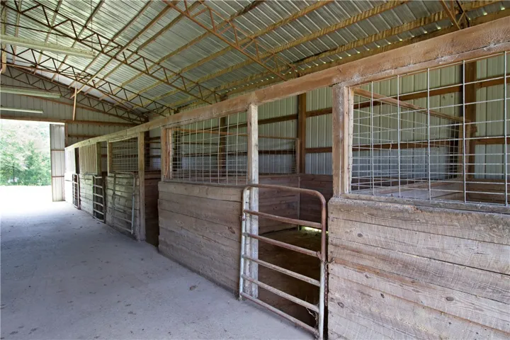 A well-maintained barn features multiple stalls and a durable metal roof, perfect for equestrian pursuits.