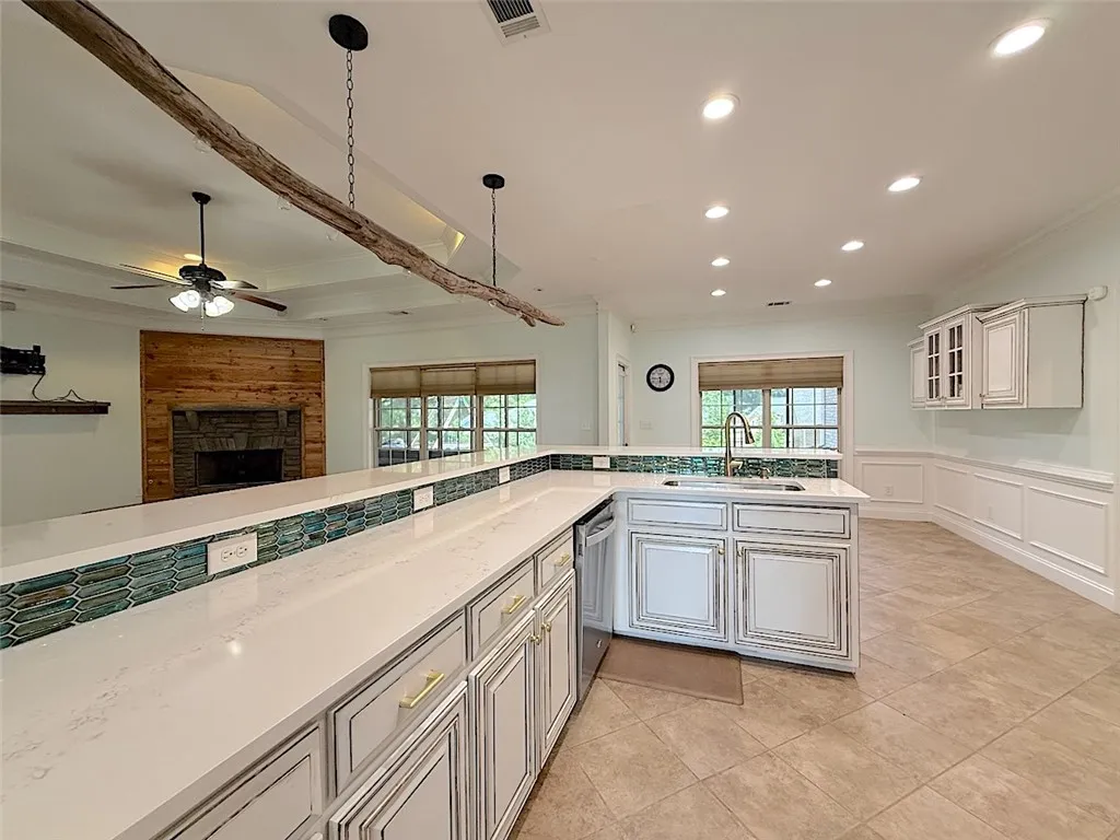 An inviting open-concept kitchen and living area feature a striking stone fireplace and a spacious island with ample counter space.