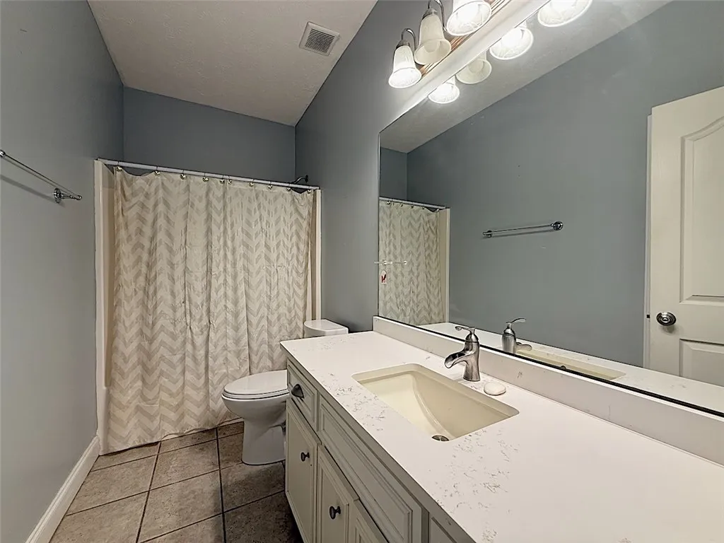 A well-lit bathroom with a vanity and a shower-tub combination.