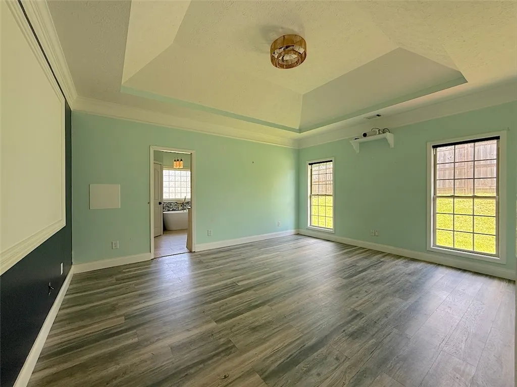 Recessed ceiling details enhance this airy room with durable wood flooring and ample natural illumination.