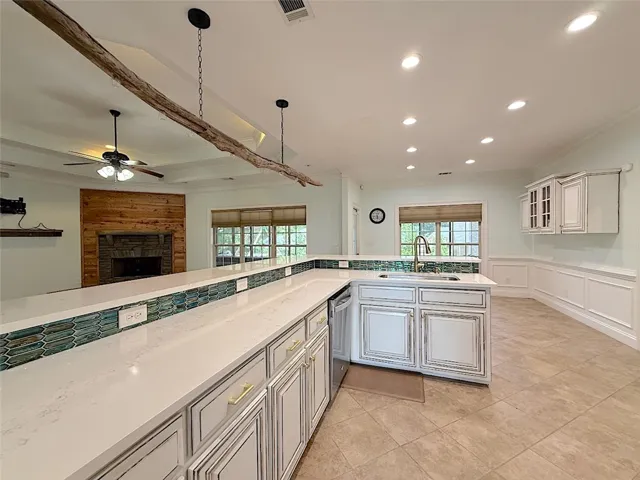 An inviting open-concept kitchen and living area feature a striking stone fireplace and a spacious island with ample counter space.